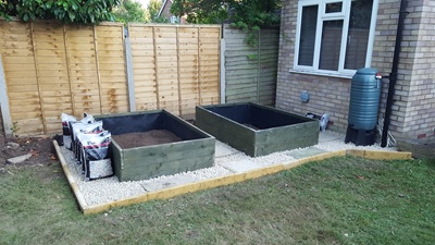 Decorative stone and pavers in place on area surrounding raised beds